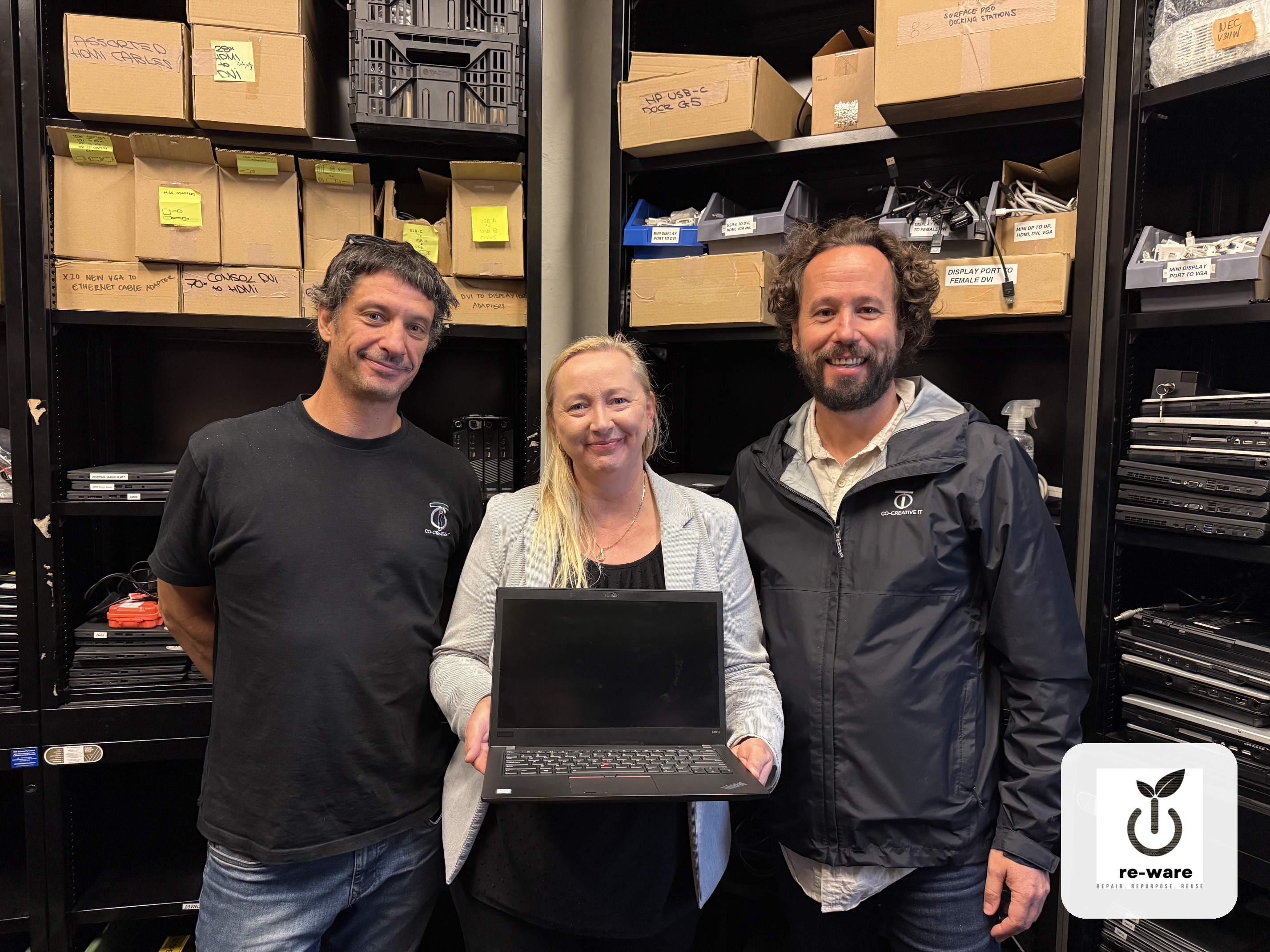 Re-Ware team with a refurbished laptop in the workshop