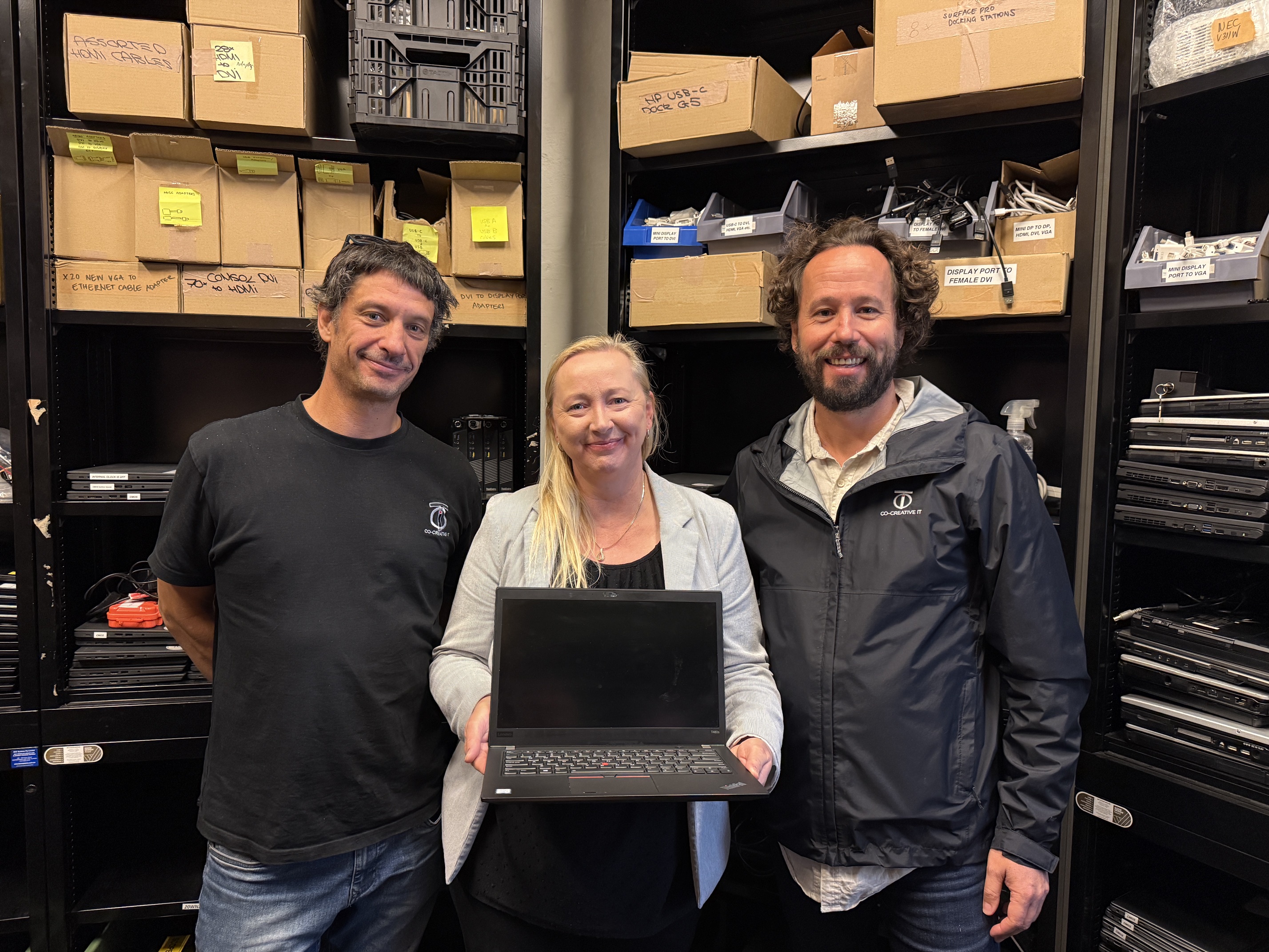 Re-Ware team with a refurbished laptop in the workshop